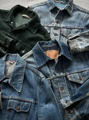Stack of denim jackets in various shades on a textured surface