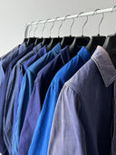 Row of blue shirts on hangers against a gray wall