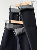 Dark jeans hanging on a rack with a white background